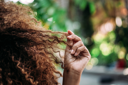 Closeup of woman hands touching her curly hair.の写真素材