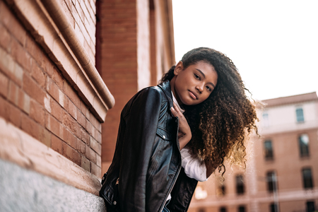 Lovely stylish girl wearing leather jacket posing outside in city street.の写真素材