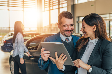 Smiling car dealer showing car files to client.の写真素材