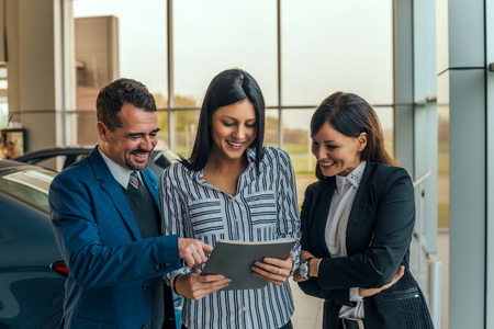 Car dealer showing contract to his customers.の写真素材