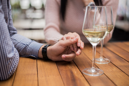 Young couple holding hands at the cafe, closeup.の写真素材