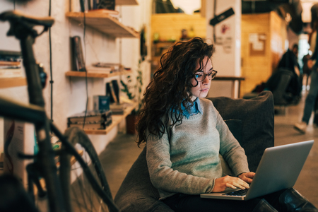 Woman with glasses using laptop in modern interior.の写真素材