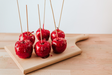 Delicious red candy apples on sticks on wooden board.の写真素材