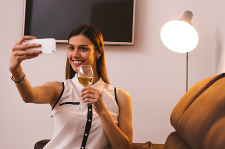 Beautiful girl taking selfie while drinking wineの写真素材
