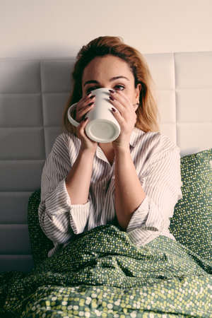 Girl in bed with cup. Need a rush of energy