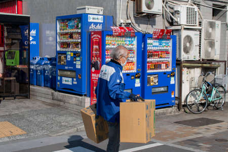 18 February 2017, Tokyo, Japan. An old man working at day time with drink machines and bicycle on the background.のeditorial素材