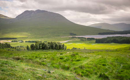 View of green field, mountain and lake, the countryside of  Scotland.の写真素材