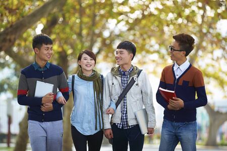 four happy asian college students walking together in the campusの写真素材