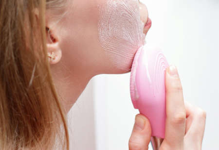 Young woman use facial massage pink brush