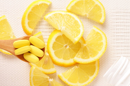 Vitamins pills on spoon with lemon slices on tableの写真素材