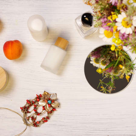 Bottles of cosmetics, mirror, flowers and fruit on wooden tableの写真素材