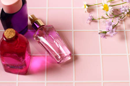 Perfume bottle on pink table with flowers
