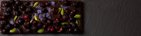 Chocolate dark bar with dried fruits on black backgroundの写真素材