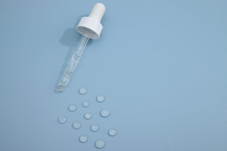 Cosmetic transparent drops and pipette on blue backgroundの写真素材