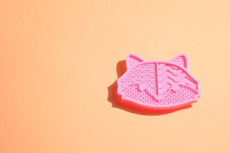 Pink silicone brush cleaner cat face shape on peach backdropの写真素材