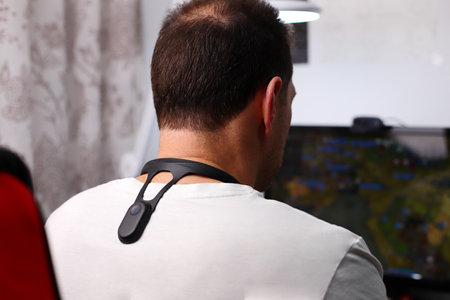 Smart posture corrector, man playing on computer, lifestyle staging