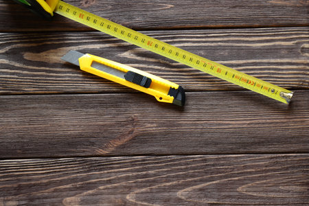 Tape measure, building knife, screws on wooden table, work toolsの写真素材