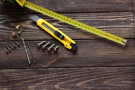 Tape measure, building knife, screws on wooden table, work toolsの写真素材