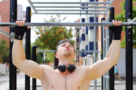 Athlete man doing exercises in horizontal bar in the street, ourdoor sport