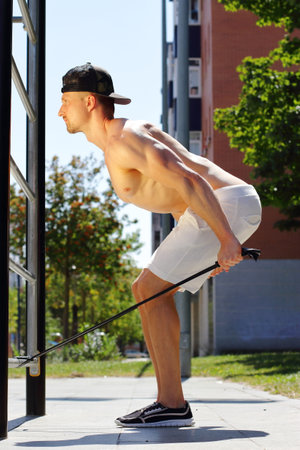 Athletic young man workout with expander in the street, outdoor training