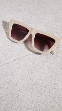 Beige sunglasses on sand, summer beach accessoriesの写真素材