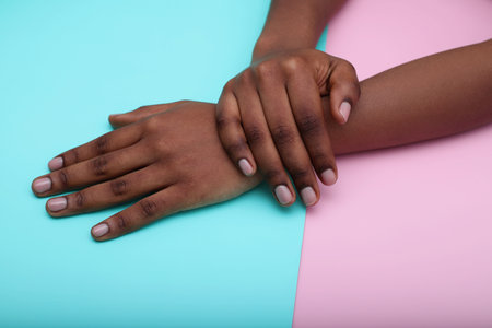 Black woman hands with nude manicure nails on colorful backgroundの写真素材