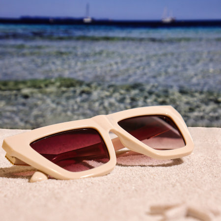 Beige fashion sunglasses on sand, summer accessories on the beachの写真素材