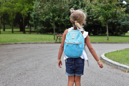 Pupil girl child with backpack going to school on the streetの写真素材