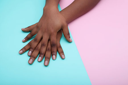 Black woman hands with nude manicure nails on colorful backgroundの写真素材