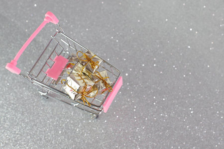 Wrapped shiny boxes for Christmas, New year in shopping trolleyの写真素材