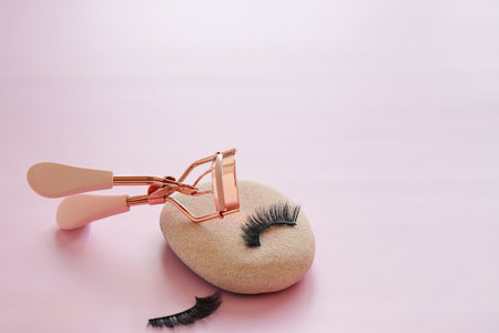 Eyelashes curler tool and false eye lashes on pink backgroundの写真素材