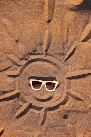 Sun in sunglasses drawn on Sand on Beach Holiday Backgroundの写真素材