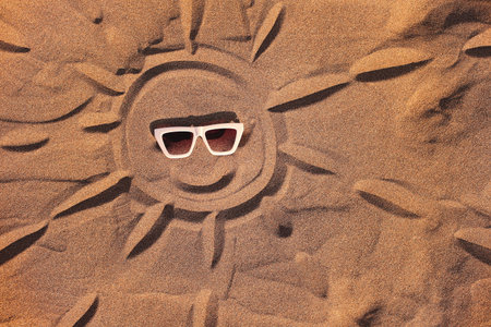 Sun in sunglasses drawn on Sand on Beach Holiday Backgroundの写真素材