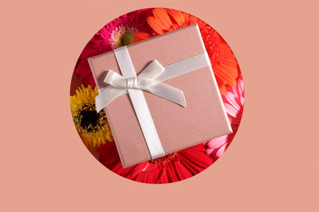 Beige present box mockup with bow on colorful gerbera flowers, present conceptの写真素材