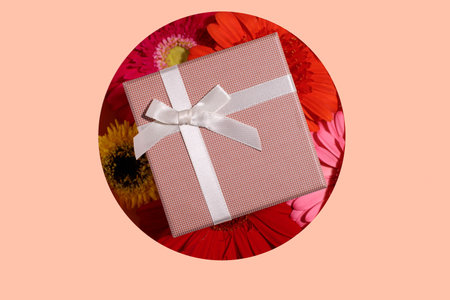 Beige present box mockup with bow on colorful gerbera flowers, present conceptの写真素材