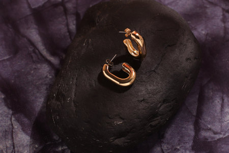 Golden luxury earrings on black stone, trendy jewelry