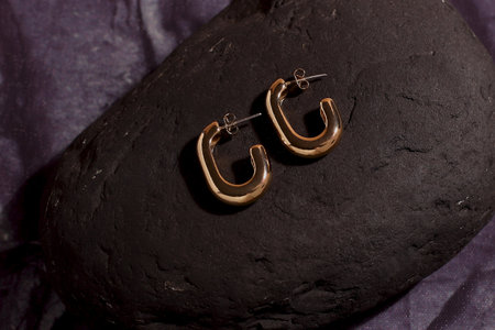 Golden luxury earrings on black stone, trendy jewelryの写真素材
