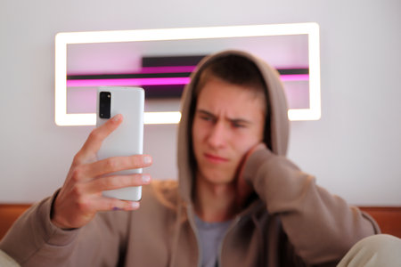 Teenager boy with smartphone, boy looking at device sitting on sofaの写真素材