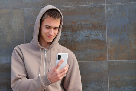 Teenager boy holding smartphone, casual clothes, teen guy on black wall backgroundの写真素材