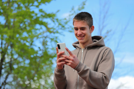 Teenager boy with smartphone on the street, looking at phoneの写真素材