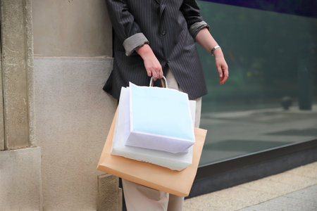 Young woman with shopping paper bags walking on street, urban fashion, shopaholic conceptの写真素材