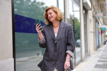 Young business woman with smartphone on her hand walking on street, urban styleの写真素材