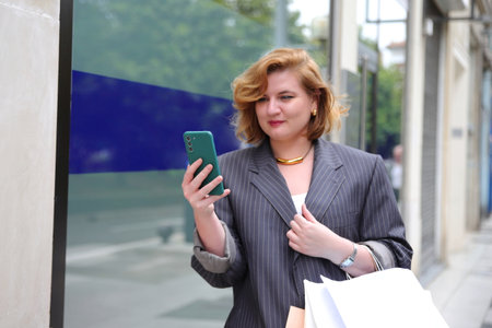 Young business woman with smartphone on her hand walking on street, urban styleの写真素材