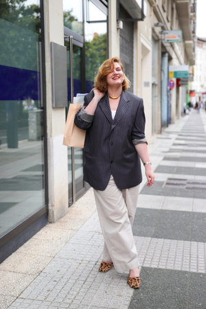 Young woman with shopping paper bags walking on street, urban fashion, shopaholic conceptの写真素材