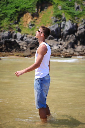 Young caucasian guy in sunglasses on the beach, casual teenager style, summer lifestyleの写真素材