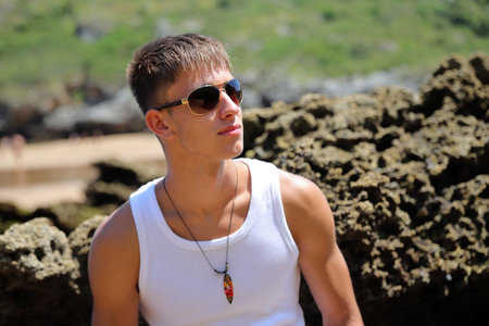 Young caucasian guy in sunglasses on the beach, casual teenager style, summer lifestyleの写真素材