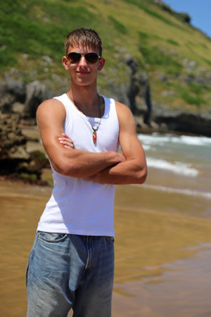 Young caucasian guy in sunglasses on the beach, casual teenager style, summer lifestyleの写真素材