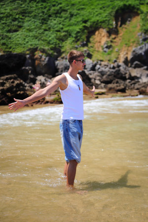 Young caucasian guy in sunglasses on the beach, casual teenager style, summer lifestyleの写真素材