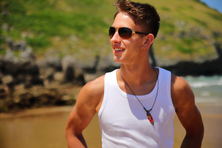 Young caucasian guy in sunglasses on the beach, casual teenager style, summer lifestyleの写真素材