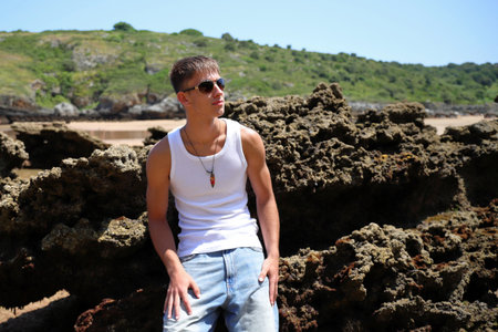 Young caucasian guy in sunglasses on the beach, casual teenager style, summer lifestyleの写真素材
